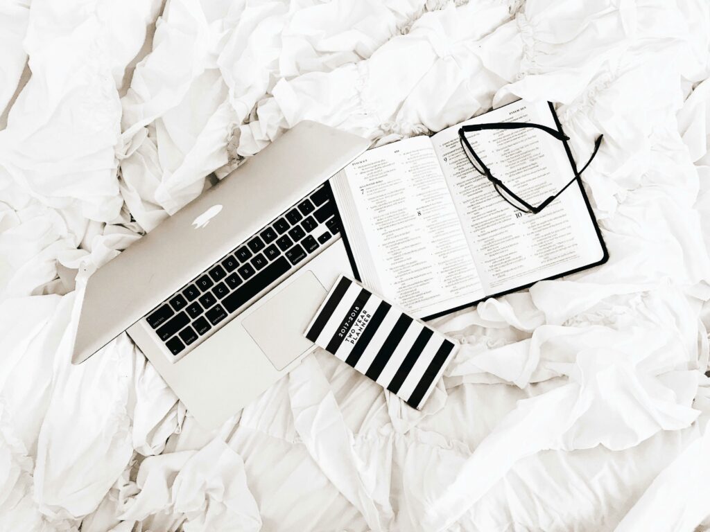 un ordinateur portable, des feuilles de papier et des stylos, symbolisant le processus d'écriture et de création d'article de blog.